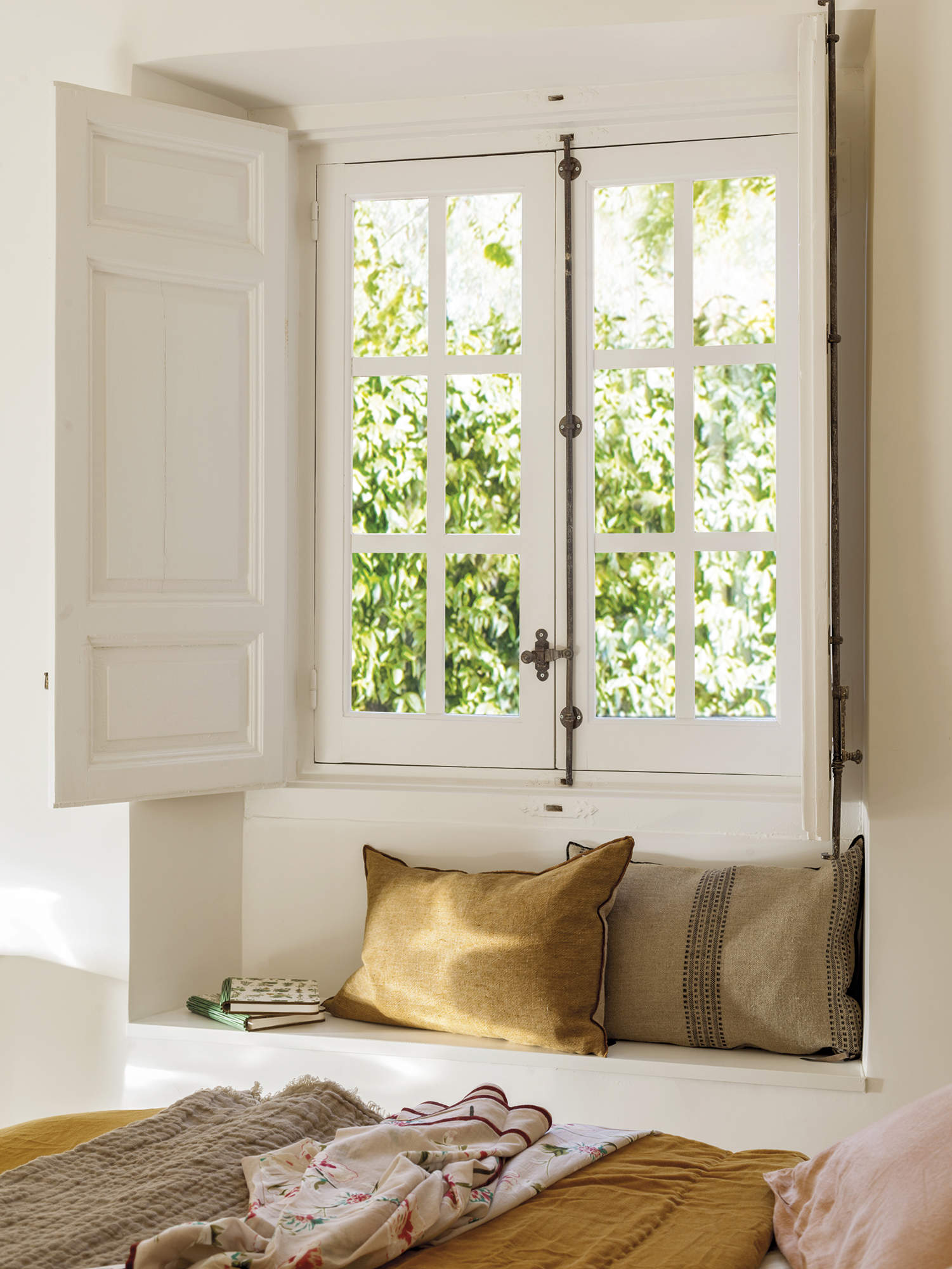 dormitorio con banco bajo ventana con cojines mostaza